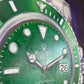 Close-up of a green Rolex watch with silver accents