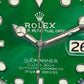 Close-up of a green Rolex watch face with 'Oyster Perpetual Date' and 'Submariner' text.