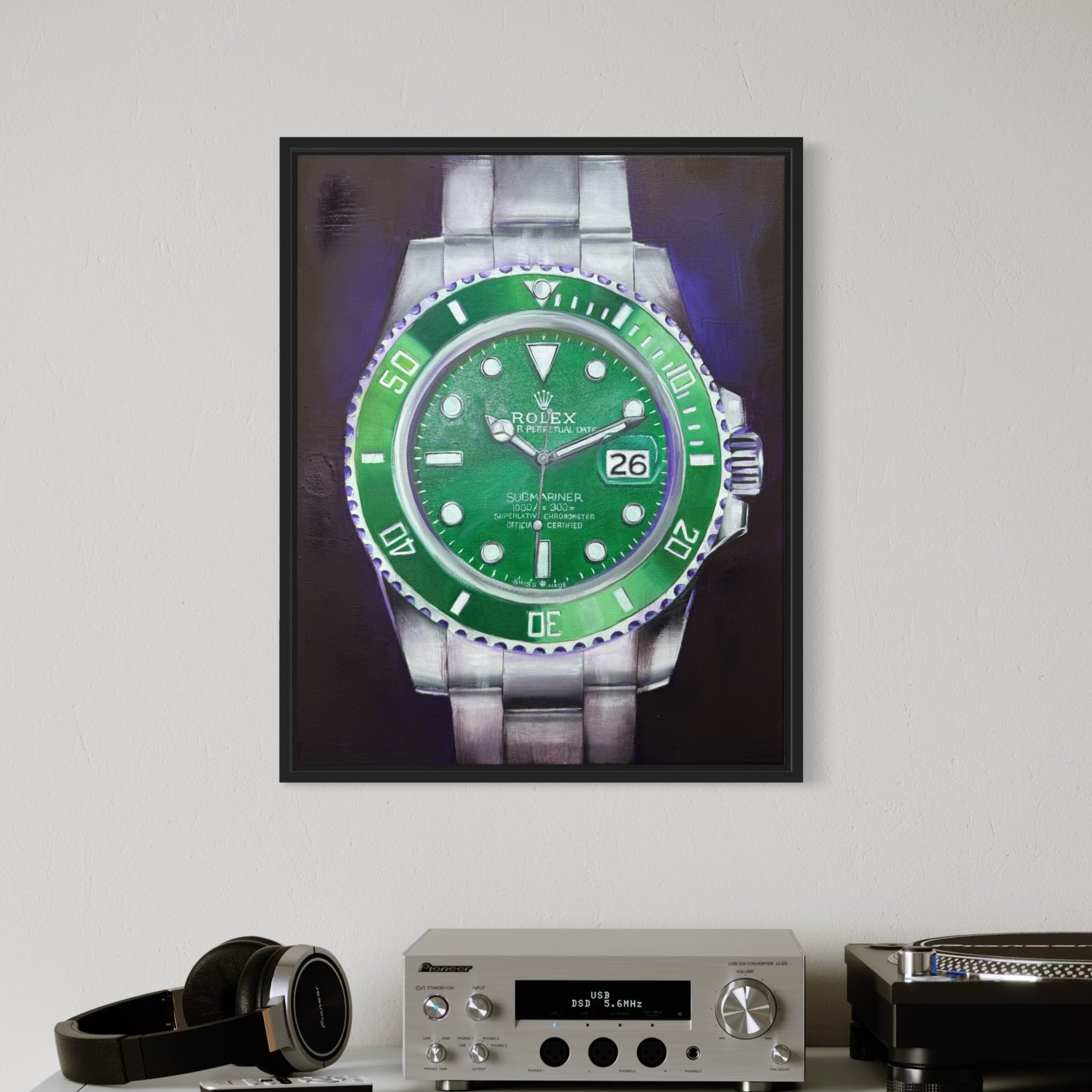 Framed picture of a green watch on a shelf with electronic equipment and books.