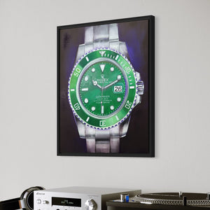 Framed picture of a green watch on a wall above a white shelf with books and electronic equipment.