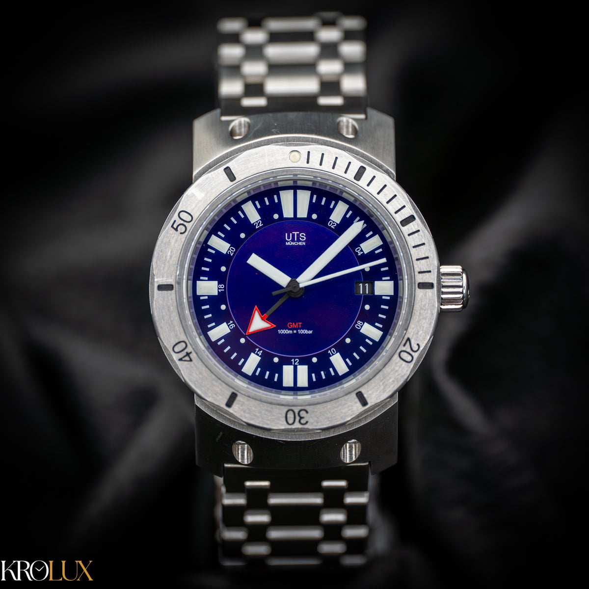 Hero shot of TS Munchen stainless steel GMT watch with blue dial on a dark background