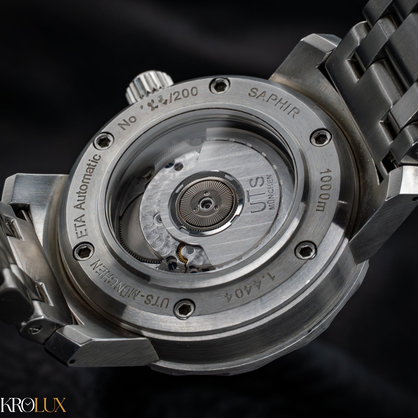Case back. UTS Munchen Close-up of a watch's mechanical movement with 'Krolux' branding.